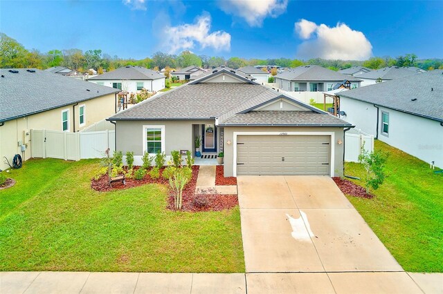 view of front of house featuring a shingled roof, a front lawn, concrete driveway, a garage, and a residential view