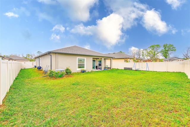 rear view of property featuring a lawn, a fenced backyard, and stucco siding