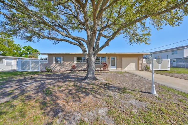 ranch-style home with an attached garage, concrete driveway, and fence