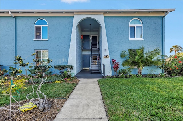 view of front of home featuring a front yard, stairway, and stucco siding