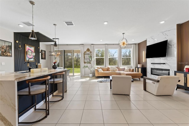 living room featuring light tile patterned floors, visible vents, recessed lighting, and a fireplace