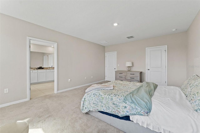 bedroom featuring baseboards, visible vents, ensuite bathroom, and light carpet