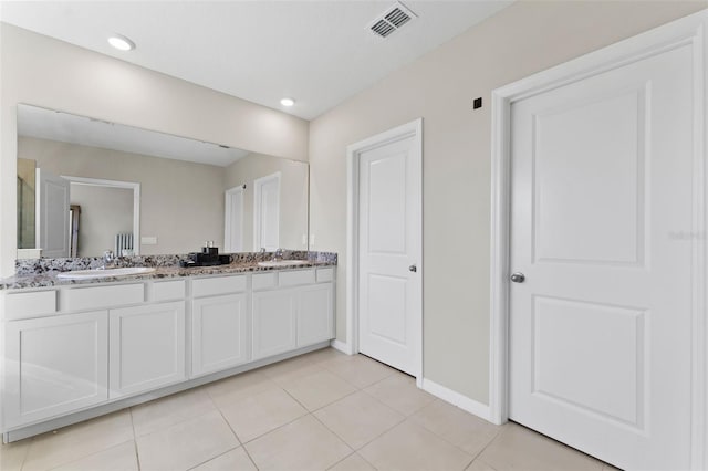 bathroom featuring tile patterned flooring, double vanity, visible vents, and a sink