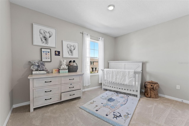 bedroom featuring light colored carpet, a crib, and baseboards