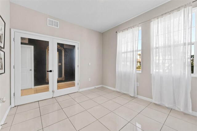 spare room featuring visible vents, baseboards, light tile patterned flooring, and french doors