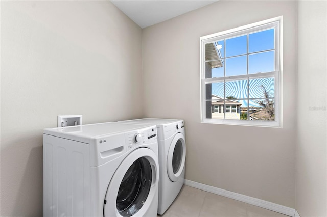 washroom featuring washer and dryer, baseboards, laundry area, and light tile patterned floors