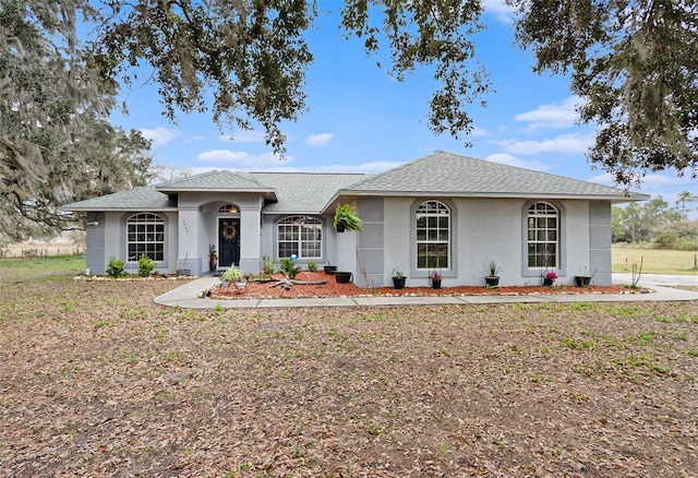 ranch-style house with a shingled roof and stucco siding