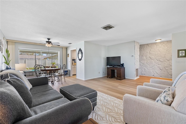 living area with visible vents, baseboards, wood finished floors, and a ceiling fan