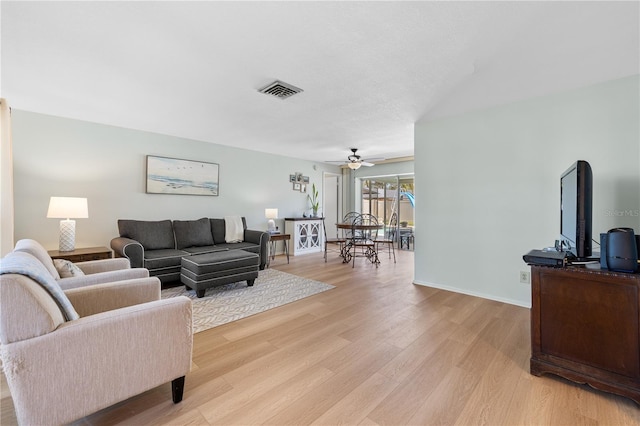 living room featuring light wood-style flooring, visible vents, and ceiling fan