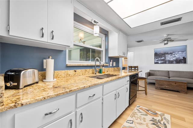 kitchen featuring visible vents, white cabinetry, black dishwasher, and a sink