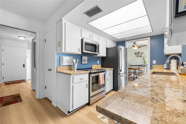 kitchen featuring visible vents, light wood finished floors, a sink, appliances with stainless steel finishes, and light countertops