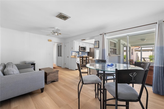 dining area with light wood-style flooring, a ceiling fan, and visible vents