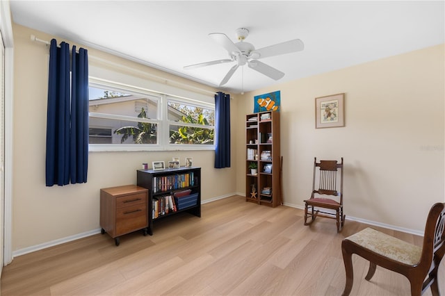 sitting room featuring a ceiling fan, light wood-style floors, and baseboards