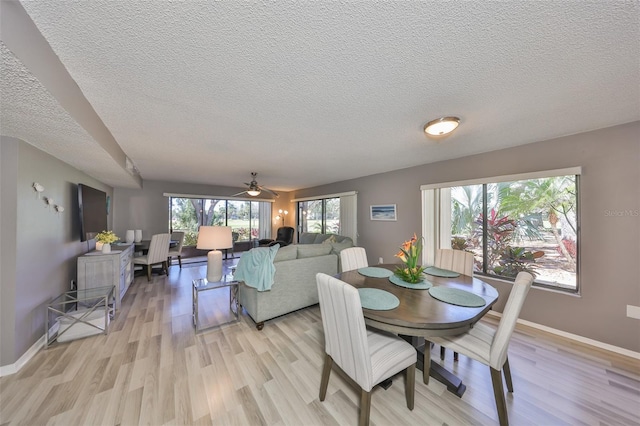 dining space featuring light wood-style floors, baseboards, and a textured ceiling