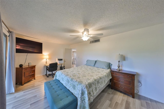 bedroom featuring visible vents, a textured ceiling, a ceiling fan, and light wood-style floors