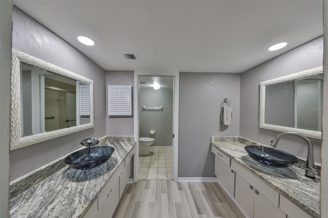 bathroom with visible vents, a stall shower, toilet, and a sink