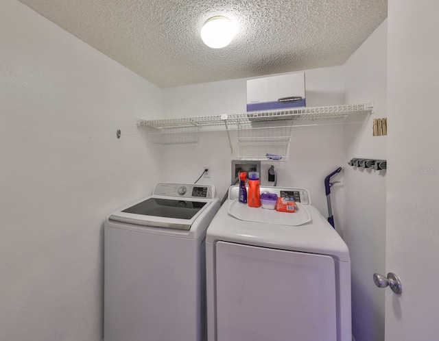 clothes washing area with laundry area, a textured ceiling, and separate washer and dryer