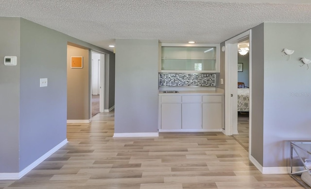 interior space with baseboards, light wood-type flooring, and a textured ceiling