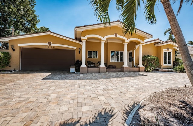 exterior space with decorative driveway, an attached garage, and stucco siding