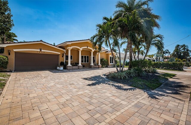 mediterranean / spanish-style house with a tile roof, decorative driveway, a garage, and stucco siding