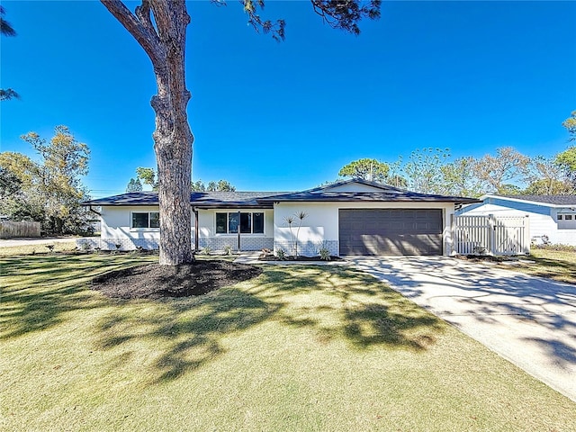 view of front facade featuring stucco siding, concrete driveway, an attached garage, a front yard, and brick siding