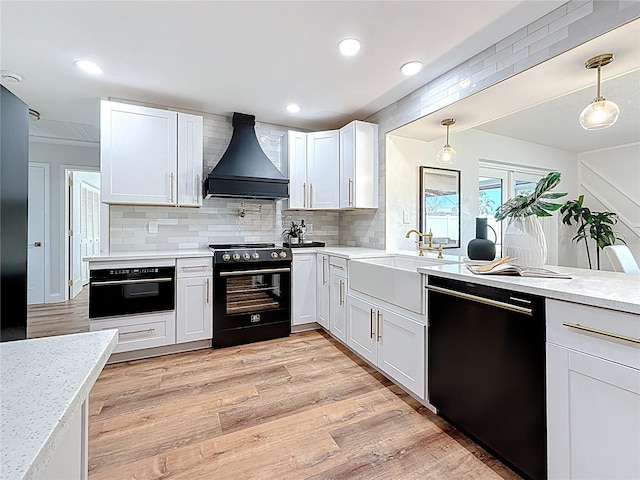 kitchen featuring light wood-type flooring, black appliances, tasteful backsplash, white cabinetry, and custom exhaust hood