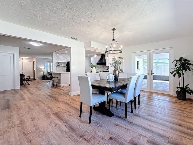 dining room featuring light wood-style flooring, french doors, baseboards, and a wealth of natural light