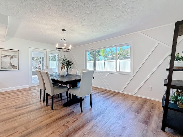 dining room with a notable chandelier, french doors, a textured ceiling, and wood finished floors