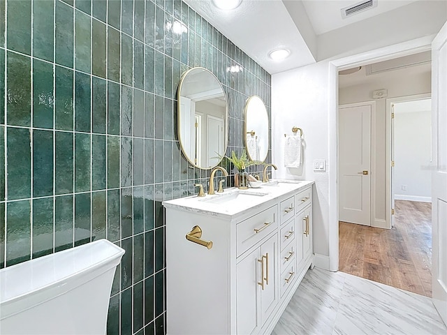 full bath featuring a sink, visible vents, and tile walls