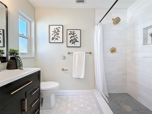 bathroom with baseboards, toilet, vanity, and a tile shower