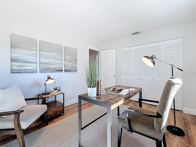 office featuring wood finished floors, visible vents, and baseboards