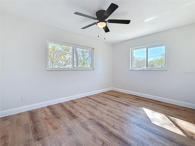 empty room with a wealth of natural light, baseboards, and wood finished floors