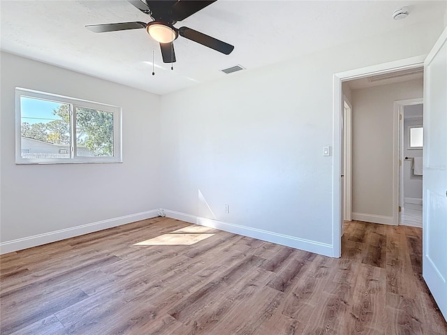 empty room featuring visible vents, ceiling fan, baseboards, and wood finished floors