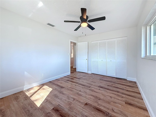 unfurnished bedroom featuring visible vents, a ceiling fan, wood finished floors, a closet, and baseboards