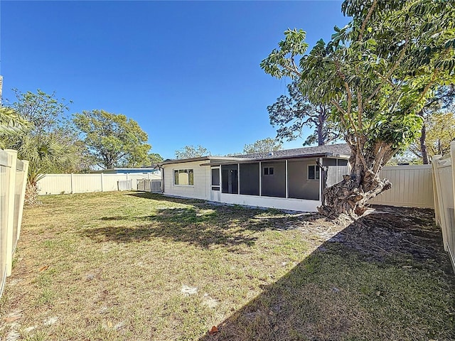 rear view of house featuring a yard, a fenced backyard, and a sunroom