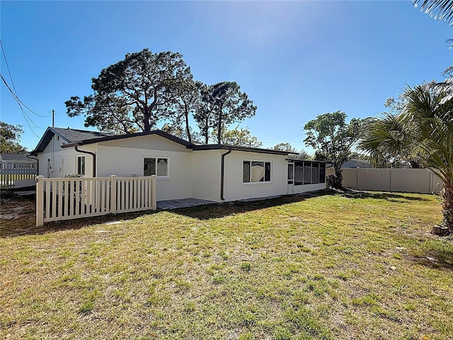 rear view of property featuring fence and a lawn