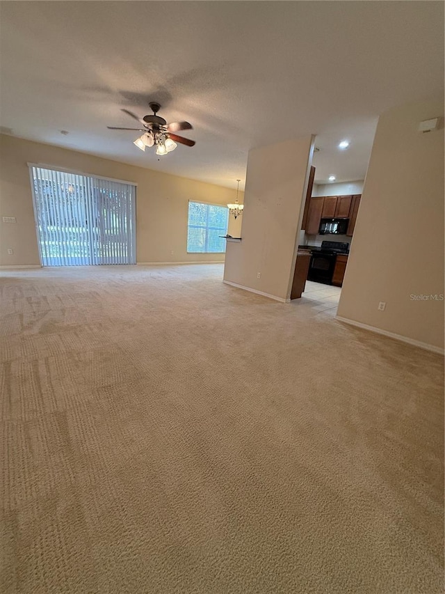 empty room featuring baseboards, light colored carpet, and ceiling fan with notable chandelier