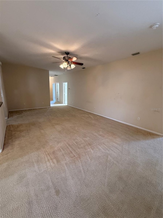 empty room featuring visible vents, baseboards, light colored carpet, and ceiling fan