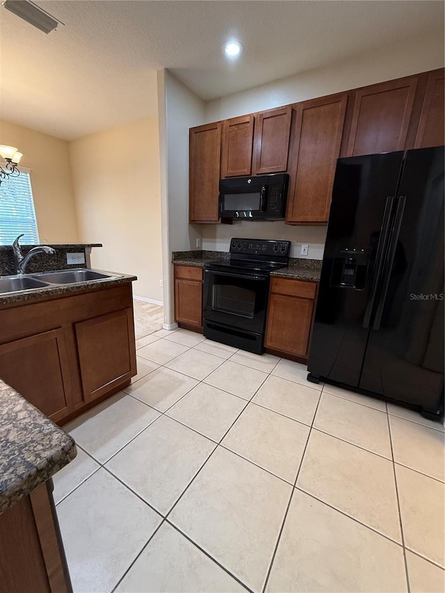 kitchen featuring a sink, dark countertops, black appliances, and light tile patterned floors