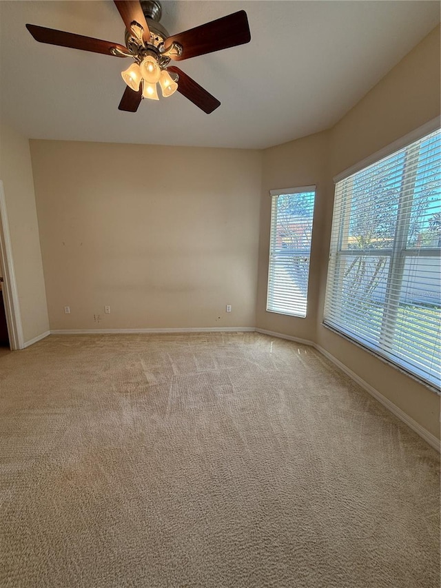 empty room with light colored carpet, baseboards, and ceiling fan