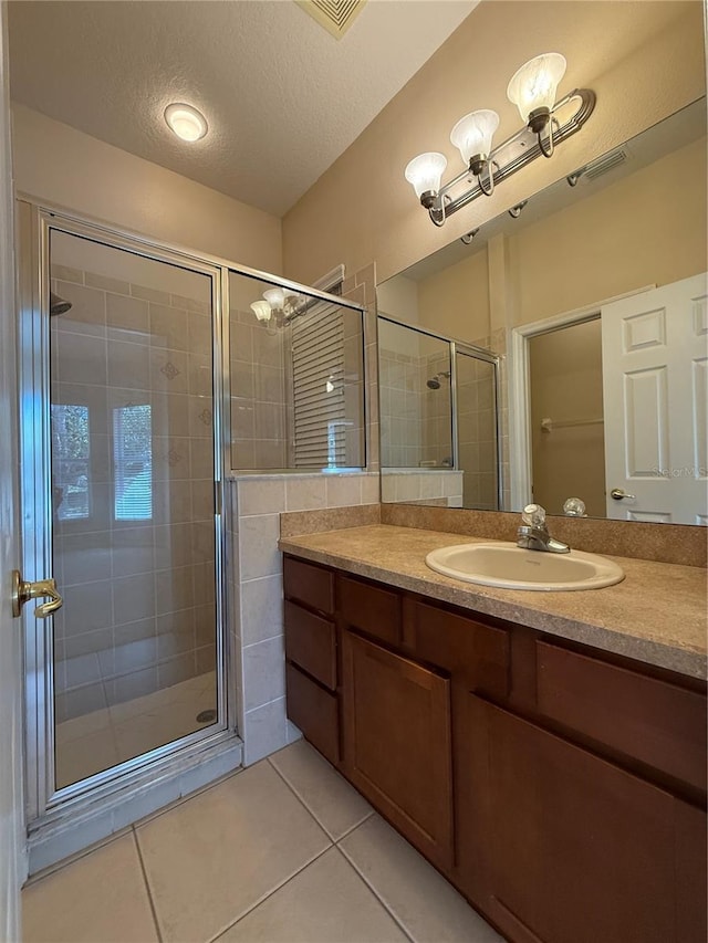 full bathroom featuring visible vents, a stall shower, a textured ceiling, tile patterned flooring, and vanity