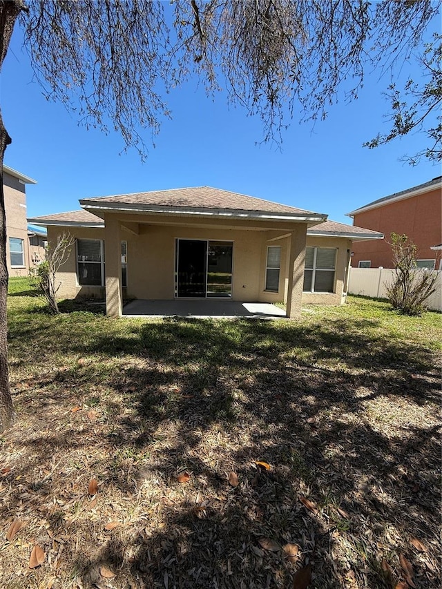 back of house featuring a shingled roof, fence, stucco siding, a yard, and a patio