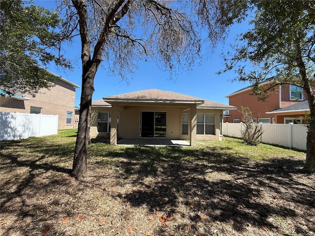 rear view of property featuring a patio, fence, a lawn, and stucco siding