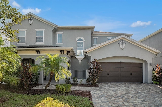 view of front of house featuring stucco siding, decorative driveway, and an attached garage