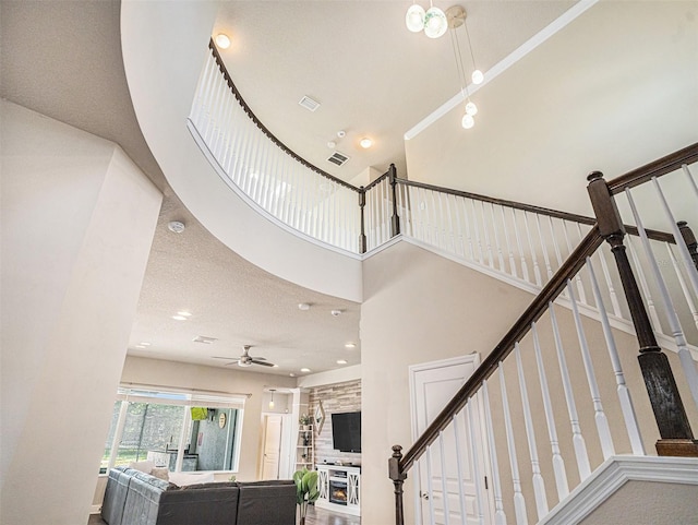 staircase with visible vents, a towering ceiling, and a ceiling fan