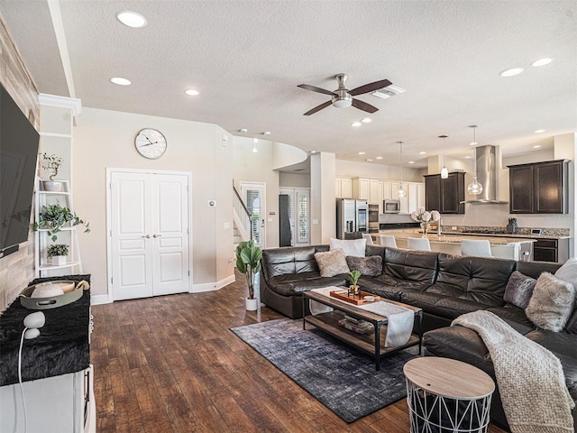 living area with stairway, visible vents, ceiling fan, dark wood-type flooring, and a textured ceiling