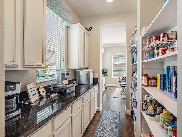 kitchen with dark wood finished floors, dark stone counters, and baseboards