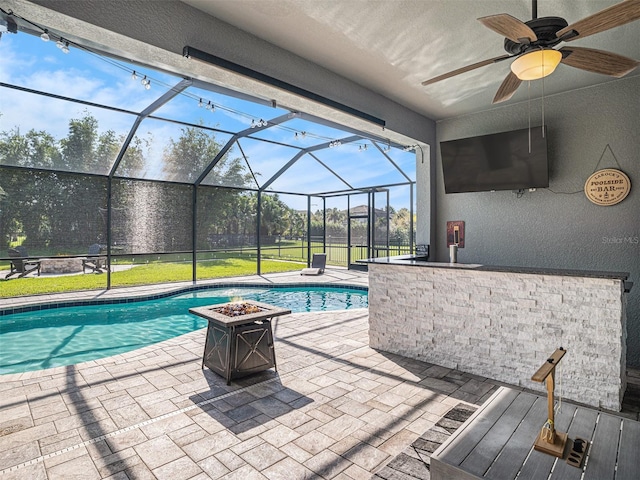 outdoor pool with glass enclosure, a patio, a ceiling fan, and an outdoor fire pit