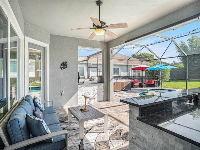 view of patio with outdoor lounge area, glass enclosure, a ceiling fan, and outdoor dry bar