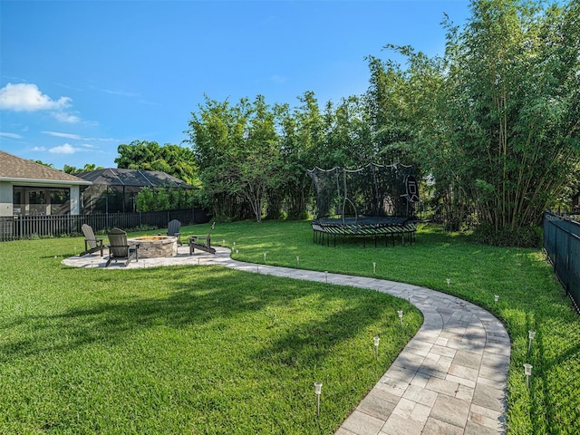 view of yard with a patio area, a trampoline, a fire pit, and a fenced backyard